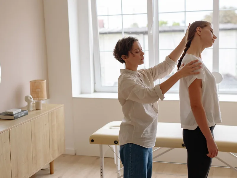 A physical therapist assessing a patient&rsquo;s shoulder by hand